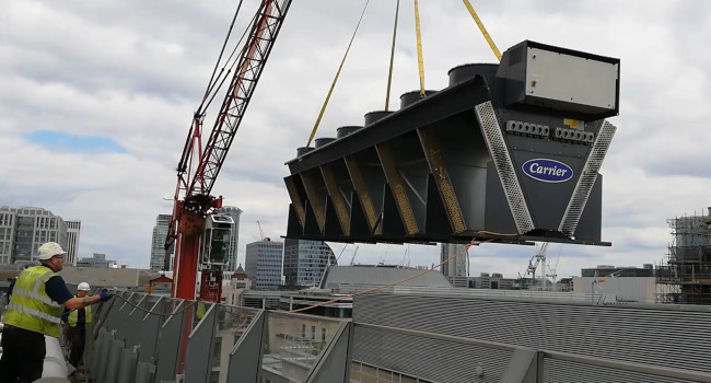 Photo at roof level of crane lifting new dry cooler.