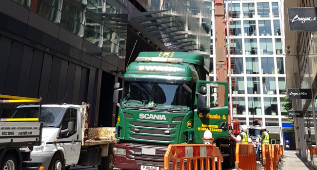 Photo of crane lifting new dry cooler to roof level.